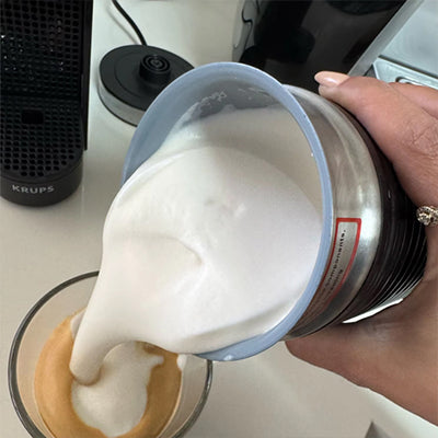 Mousseur à Lait électrique versant du lait mousseux dans une tasse